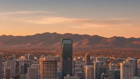 City skyline at sunset with autumn foliage and mountains in the background, showcasing a blend of urban and natural landscapes under a clear sky.