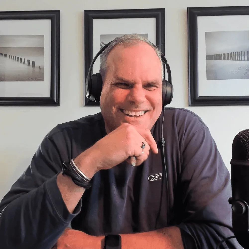 Man wearing a “Bull Bitcoin” shirt speaking on camera in a home office setup.