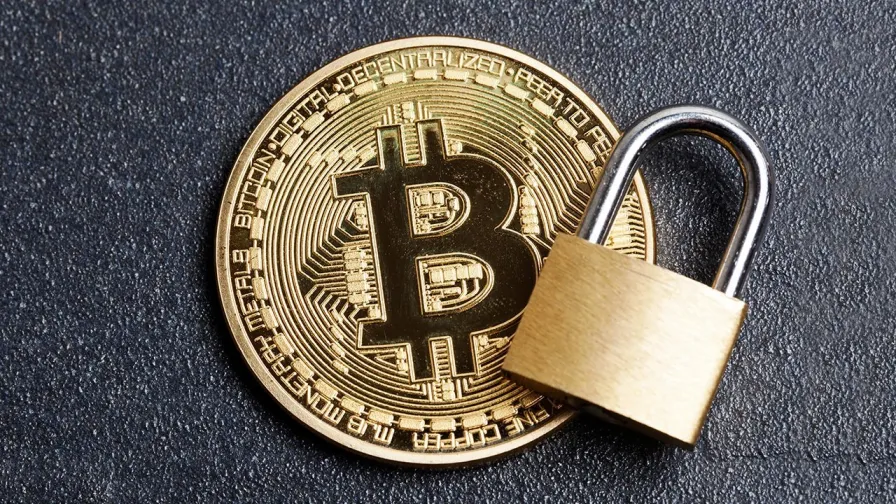 Gold Bitcoin coin with a padlock placed on top, symbolizing security and protection.